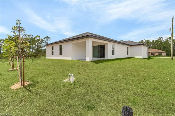 Back of house featuring a lawn and stucco siding