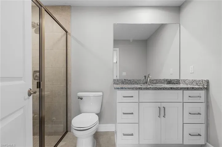 Bathroom featuring a shower stall, toilet, and vanity