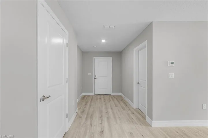 Corridor with light wood-style flooring and baseboards