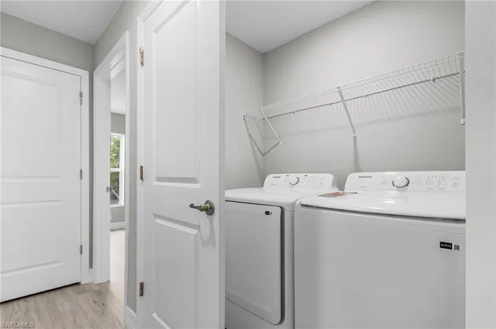 Clothes washing area featuring light wood-style floors and washing machine and clothes dryer