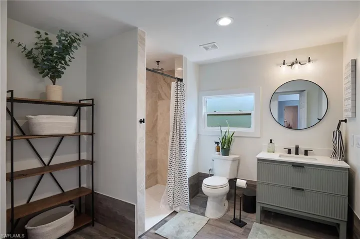 Bathroom featuring vanity, a walk in shower, wood finished floors, and recessed lighting