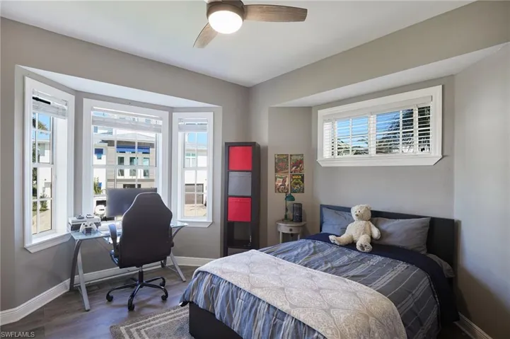 Bedroom with wood finished floors, ceiling fan, and a desk