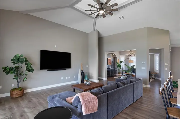 Living room with a ceiling fan, a chandelier, high vaulted ceiling, and beam ceiling