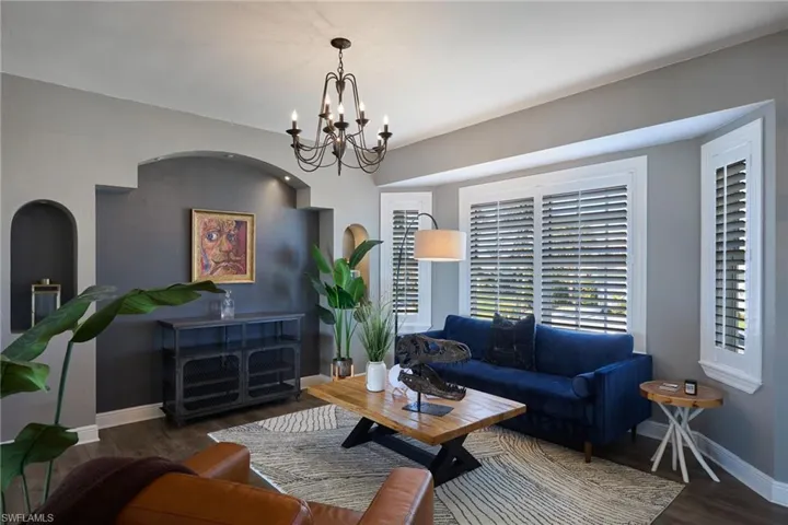 Living area featuring dark wood finished floors, arched walkways, and a chandelier