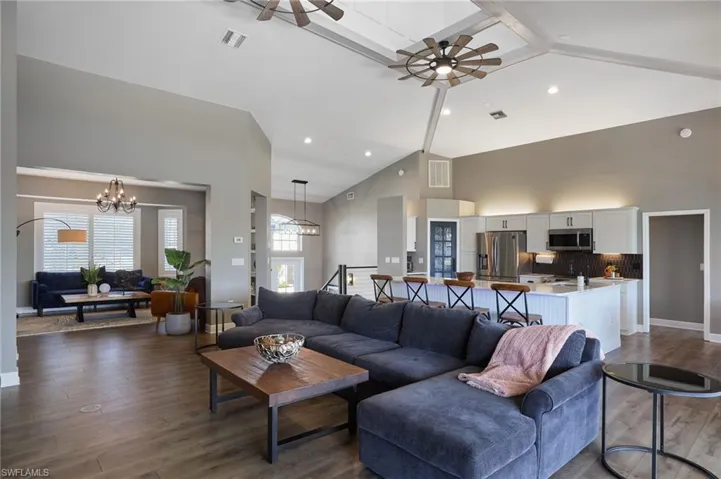Living area with high vaulted ceiling, a ceiling fan, a chandelier, and recessed lighting