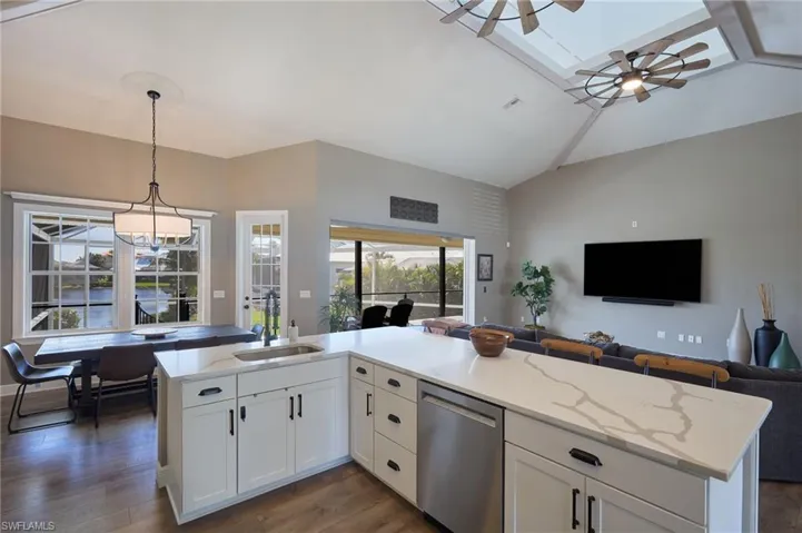 Kitchen with open floor plan, white cabinetry, a skylight, a ceiling fan, and light stone counters
