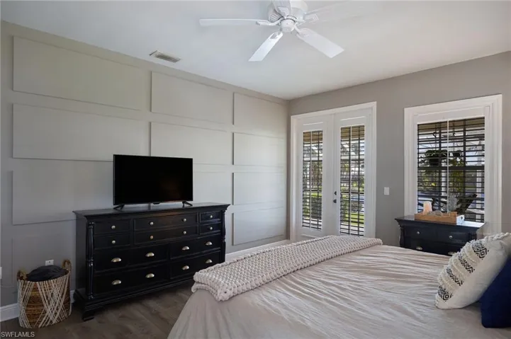 Bedroom with access to outside, dark wood-style floors, ceiling fan, and a decorative wall
