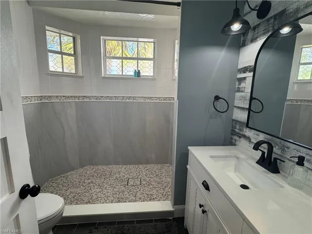 Full bath with vanity, walk in shower, and dark tile patterned floors