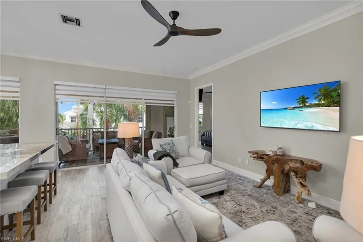 Living room featuring crown molding, a ceiling fan, healthy amount of natural light, and light wood-style flooring