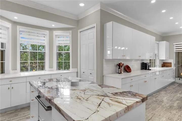 Kitchen featuring light wood-type flooring, recessed lighting, white cabinetry, crown molding, and backsplash