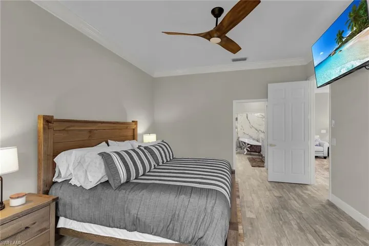 Bedroom with wood finished floors, ornamental molding, and ceiling fan