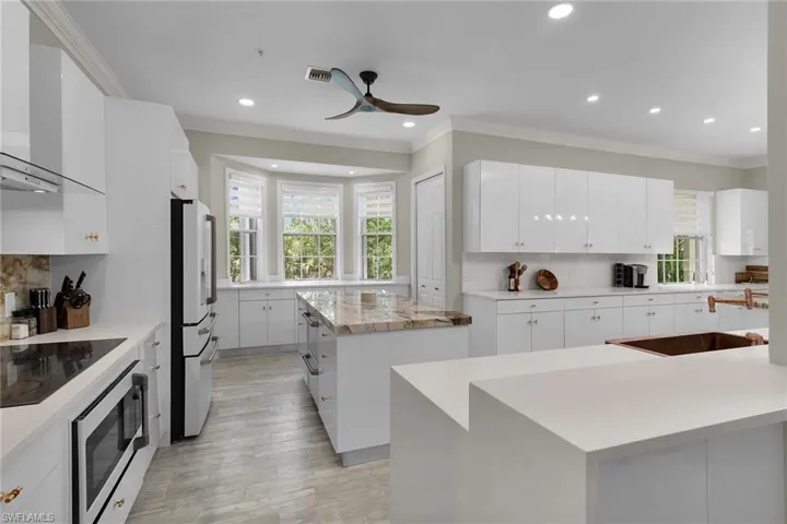 Kitchen featuring a center island, black electric stovetop, wall chimney exhaust hood, plenty of natural light, and recessed lighting