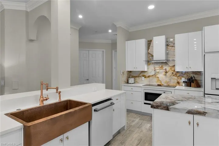 Kitchen with wall chimney exhaust hood, dishwasher, wall oven, light wood-type flooring, and decorative backsplash