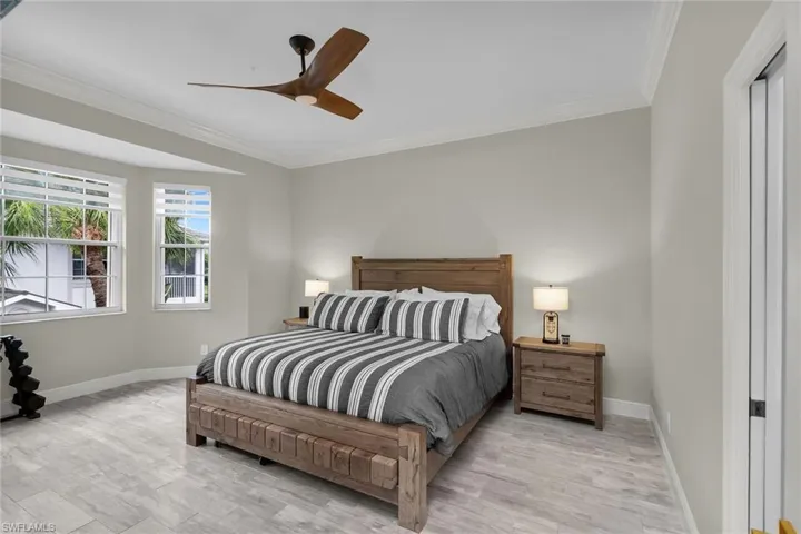Bedroom with crown molding, light wood-type flooring, and a ceiling fan