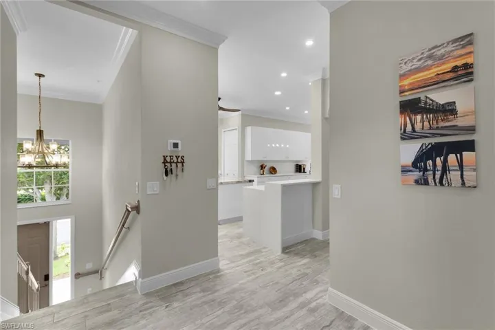Corridor with an upstairs landing, a chandelier, crown molding, light wood-type flooring, and recessed lighting