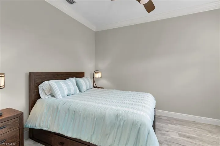 Bedroom featuring crown molding, light wood-style flooring, and ceiling fan