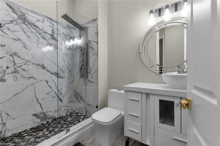 Bathroom with a marble finish shower, vanity, and wood finished floors
