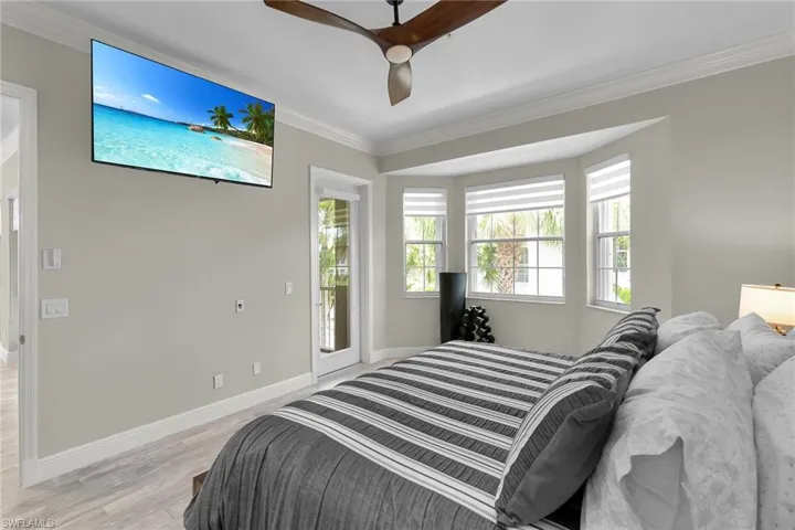 Bedroom with crown molding, light wood-style floors, ceiling fan, and access to exterior