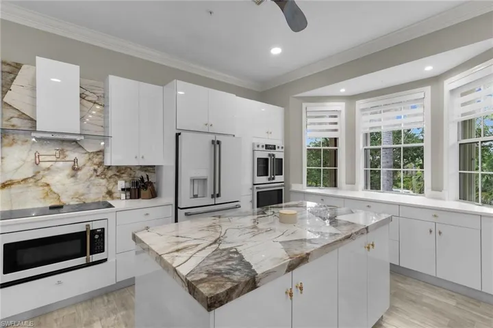 Kitchen with white appliances, ventilation hood, light wood-type flooring, tasteful backsplash, and ornamental molding