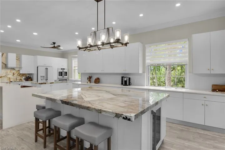 Kitchen with a kitchen island, refrigerator with ice dispenser, oven, ornamental molding, and recessed lighting