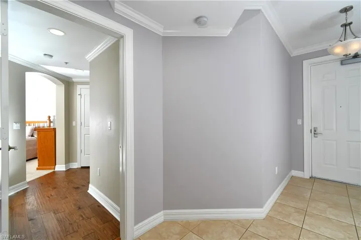 Foyer featuring crown molding, arched walkways, and wood finished floors