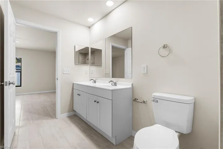Bathroom featuring a double vanity with white cabinetry, a dual-sink countertop, and two framed mirrors