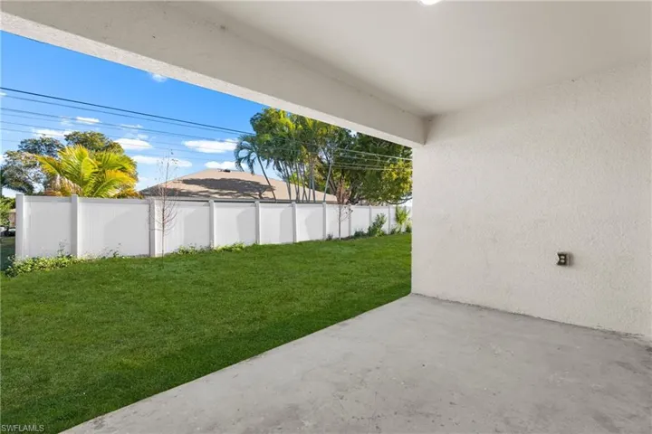 Covered patio with a concrete slab, leading to a vibrant green lawn