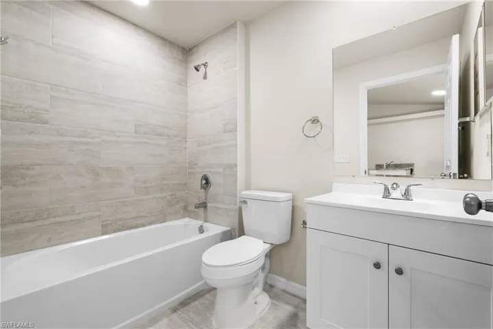 Bathroom featuring a white vanity with integrated sink, chrome fixtures, and a large wall-mounted mirror