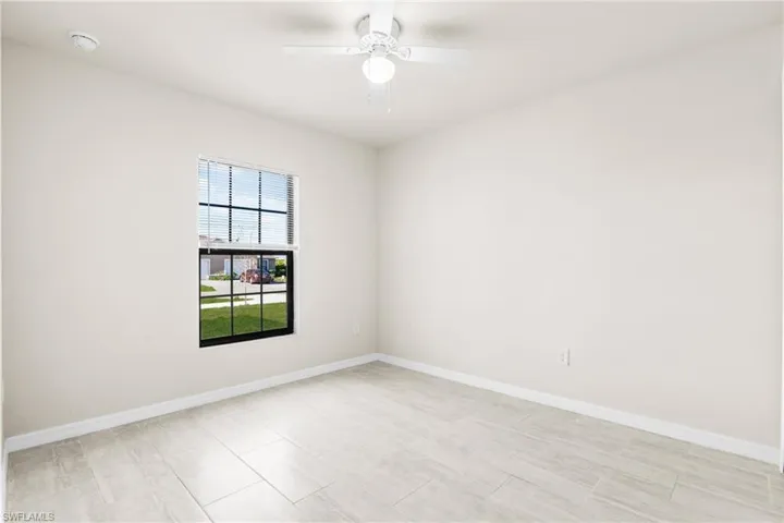 Neutral-toned room featuring light-colored tile flooring, white baseboards, and a window with white blinds