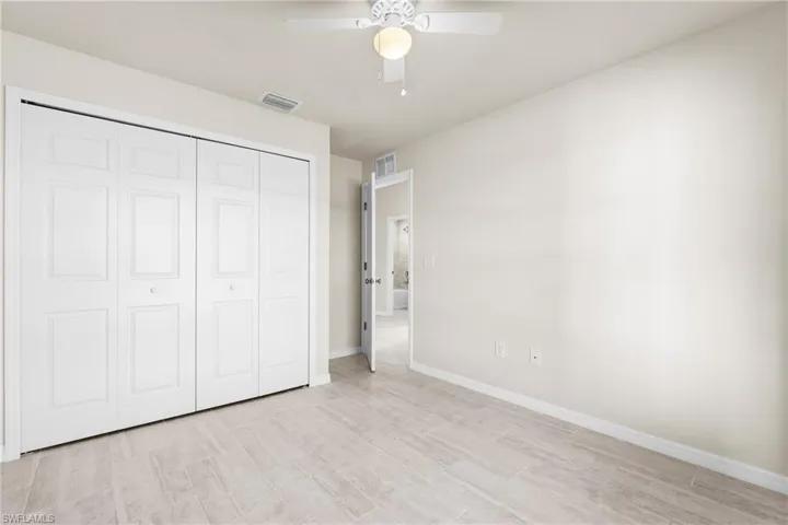 Neutral-toned interior room featuring wood-look tile flooring, white baseboards, and a ceiling fan with integrated lighting