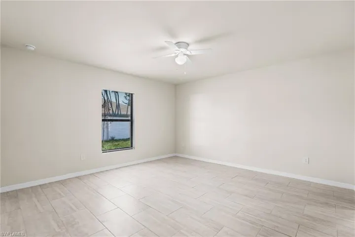 Spacious room with light-toned tile flooring, neutral wall paint, and a ceiling fan