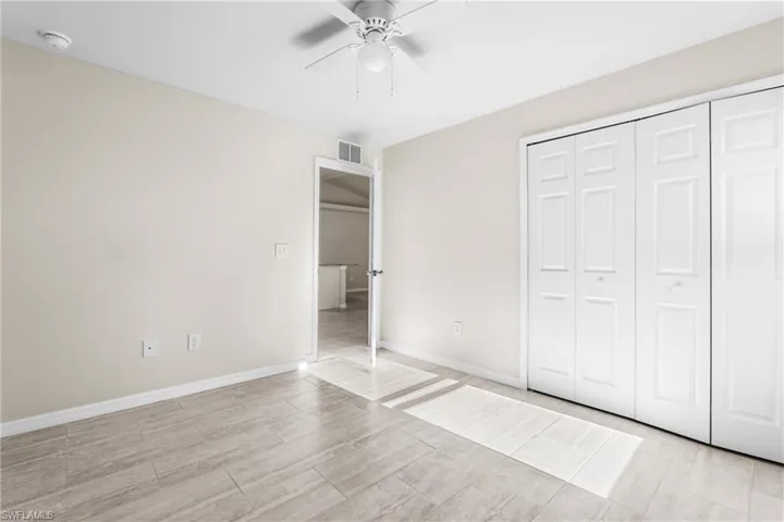 Bedroom featuring light beige wall paint, light-toned wood-finish flooring, and a ceiling fan with light fixture