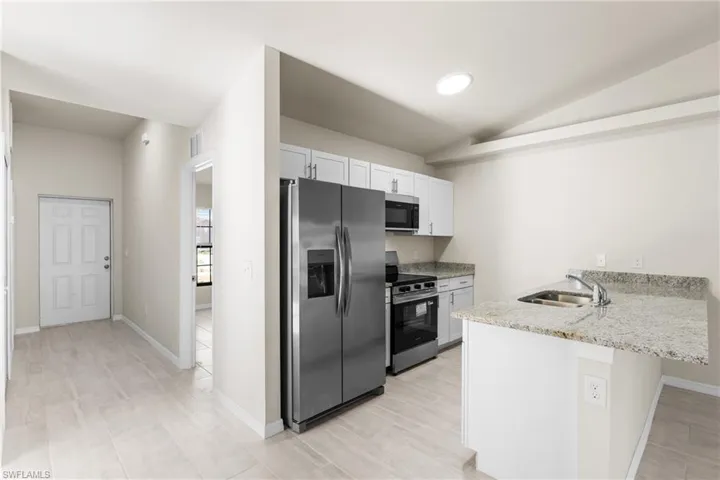 Kitchen featuring granite countertops, stainless steel appliances, white cabinetry, and a circular ceiling light fixture