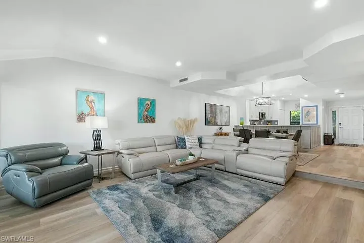 Living room with light wood-style flooring, recessed lighting, a chandelier, and lofted ceiling