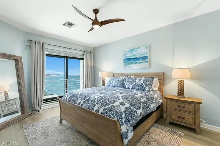 Bedroom with light wood-style floors, a water view, and a ceiling fan