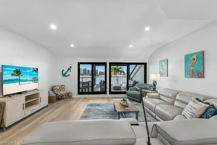 Living area with vaulted ceiling, light wood-style floors, and recessed lighting