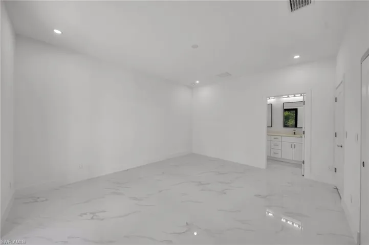 Empty room with recessed lighting, baseboards, light marble finish flooring, and a sink