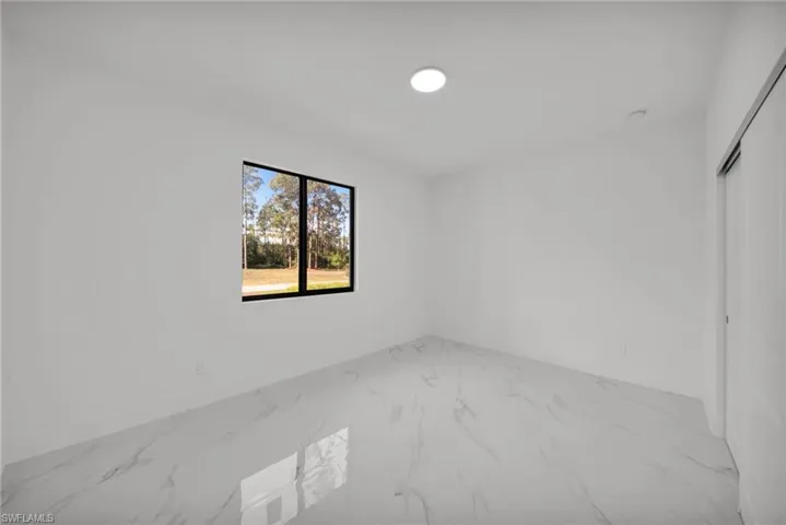 Spare room featuring marble finish floors and baseboards