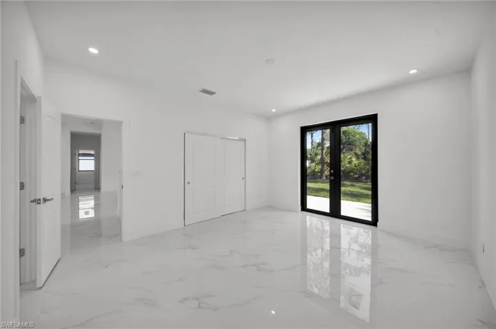 Unfurnished bedroom featuring light marble finish floors, multiple windows, recessed lighting, and access to outside