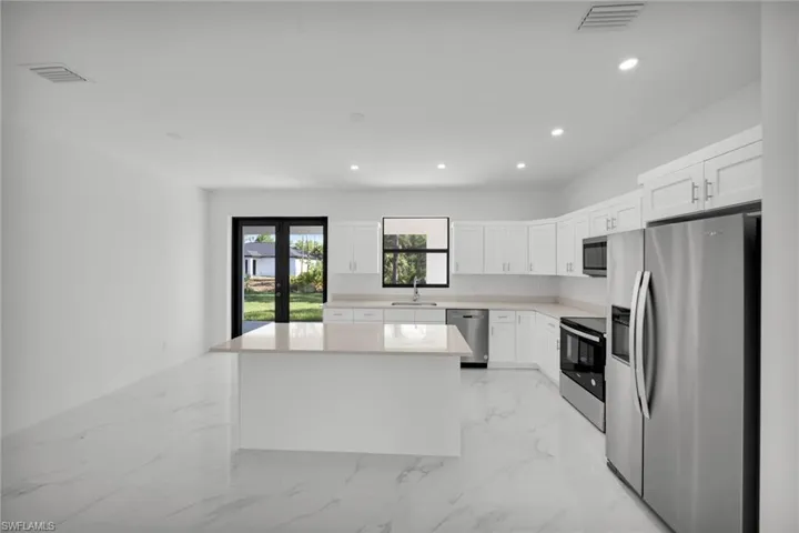 Kitchen with stainless steel appliances, a sink, recessed lighting, white cabinets, and light marble finish floors