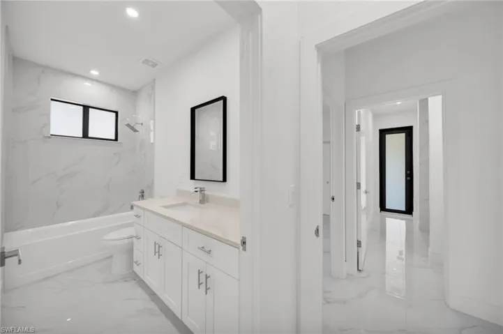Full bathroom with marble tiled flooring, toilet, vanity, tub / shower combination, and recessed lighting