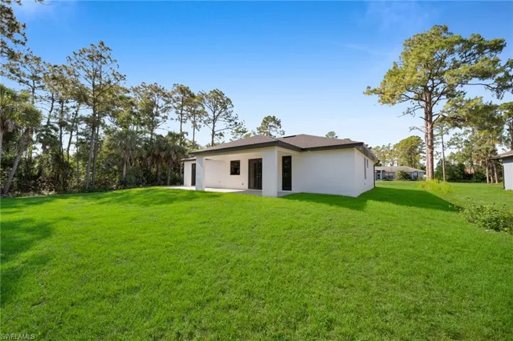 Rear view of property featuring stucco siding, a lawn, and a patio area