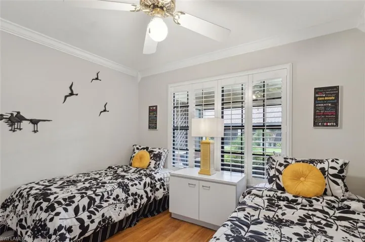 Guest Bedroom with ceiling fan, ornamental molding, and light wood-type flooring