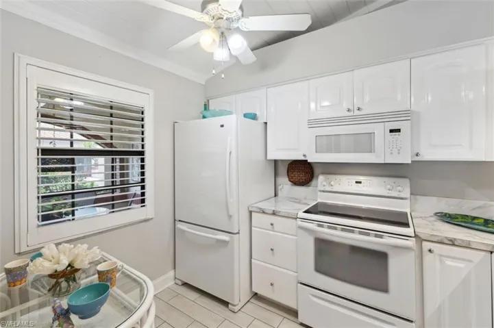 Kitchen featuring white cabinets, white appliances, vaulted ceiling, and ceiling fan