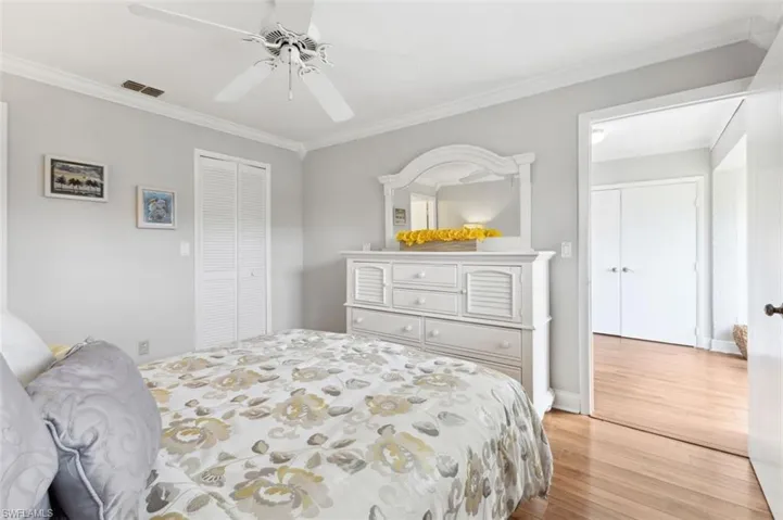Bedroom featuring crown molding, light hardwood / wood-style flooring, ceiling fan, and a closet