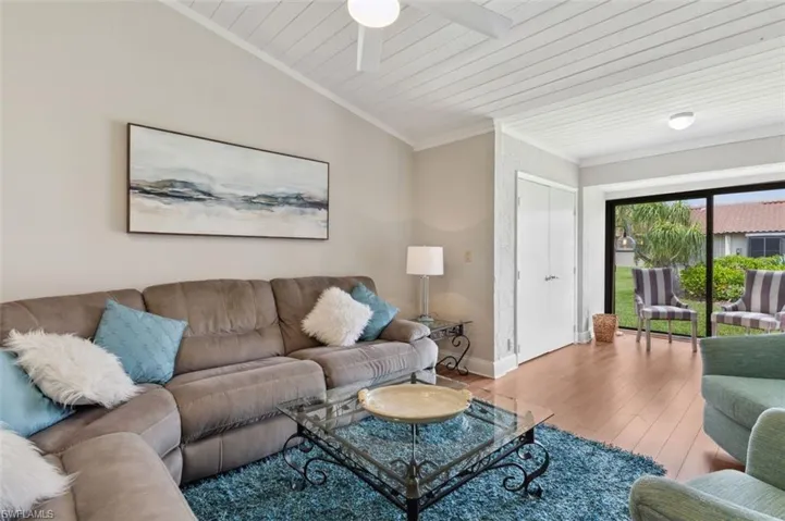 Living room featuring ornamental molding, wood-type flooring, ceiling fan, wood ceiling, and lofted ceiling