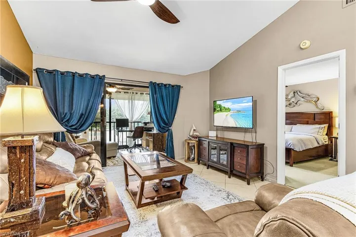 Living area featuring ceiling fan, lofted ceiling, and light tile patterned floors