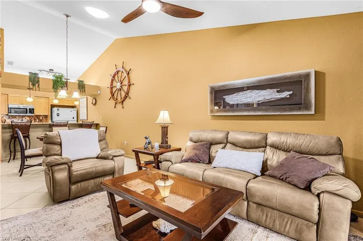 Living area featuring vaulted ceiling, a ceiling fan, and light tile patterned floors