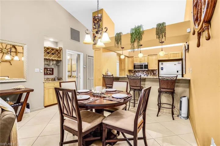 Dining room featuring light tile patterned floors, high vaulted ceiling, and a chandelier