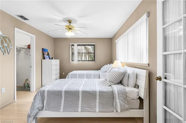 Bedroom featuring a walk in closet, light wood-type flooring, and ceiling fan